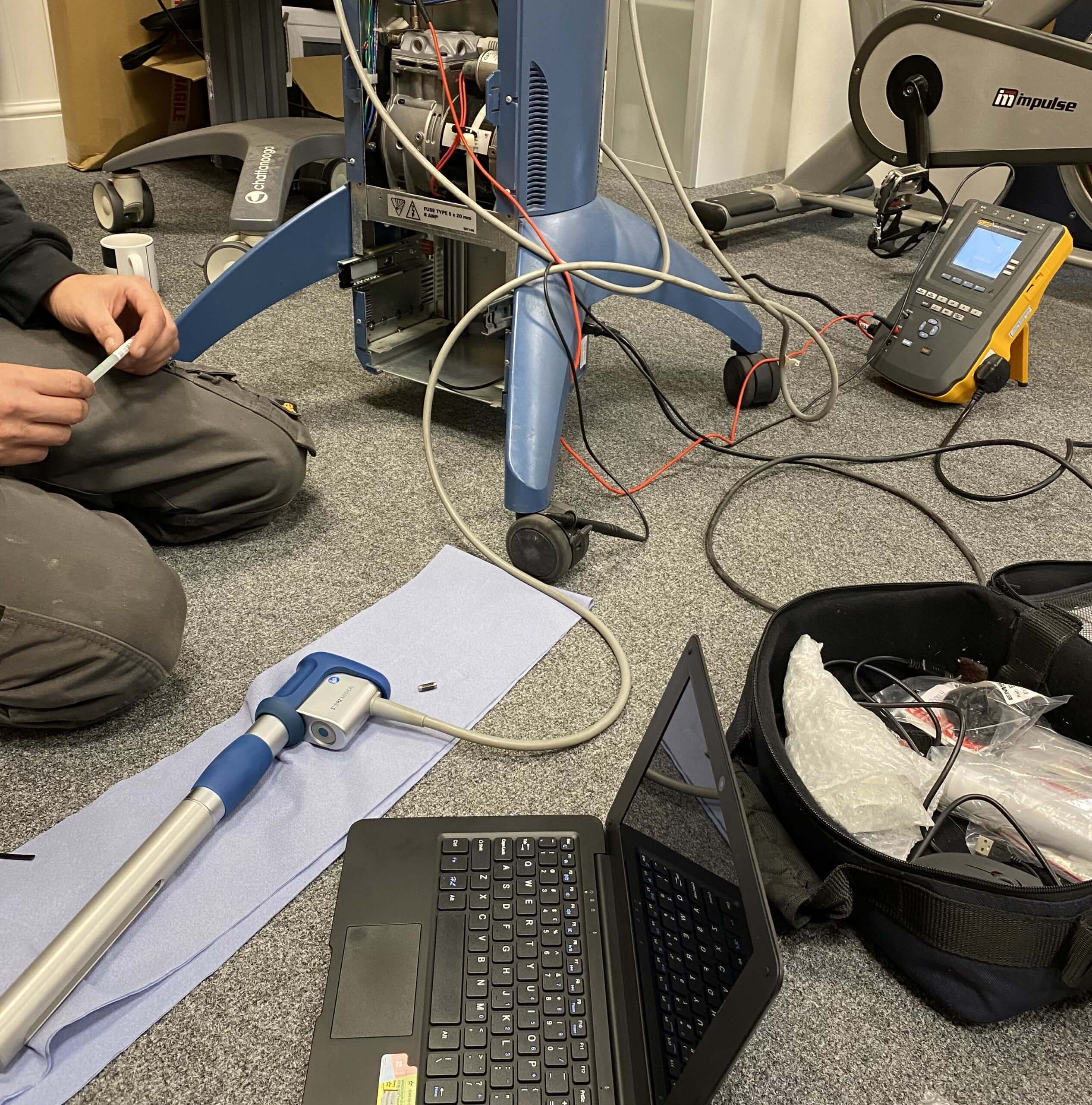 trimbio-engineer-servicing-shockwave-therapy-machine.jpg trimbio engineer servicing a shockwave therapy machine, with diagnostic testing equipment and laptop