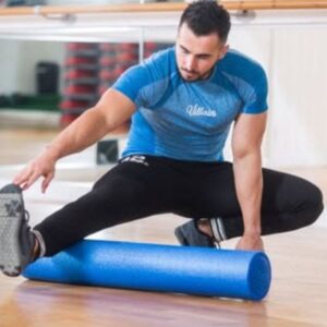 A person using a 90 x 15cm foam roller on a studio floor, demonstrating balance, alignment, and myofascial release techniques commonly used in Pilates, yoga, massage, and physiotherapy.