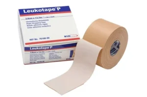 A roll of beige rigid Leukotape P with its packaging, showing high‑adhesion strapping tape used for stabilising joints and providing firm athletic support.