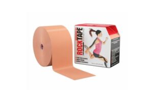 A beige roll of RockTape Big Daddy kinesiology tape beside its branded box, designed for supportive taping, pain reduction and enhanced athletic movement.