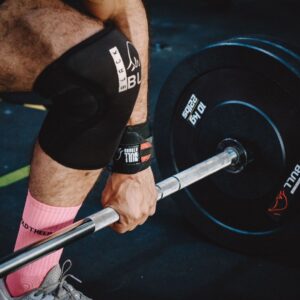 A close-up of a knee supported with kinesiology tape during strength training, showing how taping can improve stability and reduce discomfort for athletes.