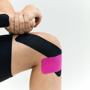 A close-up of a knee supported with kinesiology tape during strength training, showing how taping can improve stability and reduce discomfort for athletes.