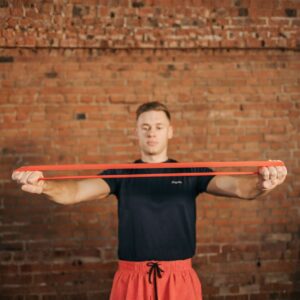 A person performing an upper‑body resistance‑band exercise indoors, demonstrating how resistance loops can be used for strength training and mobility work.