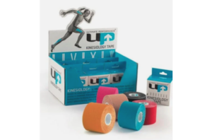 Multiple rolls of coloured UP kinesiology tape displayed in front of branded packaging, showing elastic therapeutic tape used for muscle support, injury prevention, and athletic recovery.